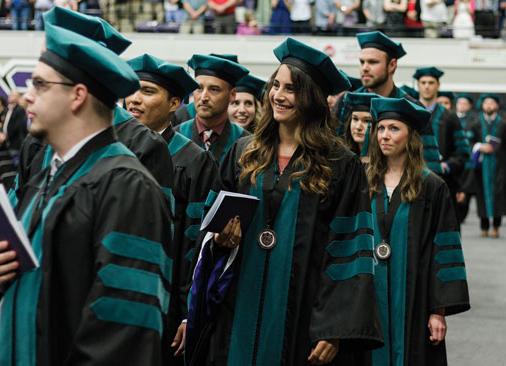 graduate students in regalia walk in commencement ceremony